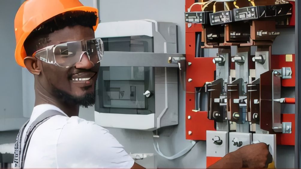 ELSIM technician in an orange hard hat and safety glasses working on switchgear in a control panel